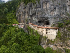 A monastery embedded in a green rocky landscape surrounded by dense forest, aerial view, Sumela