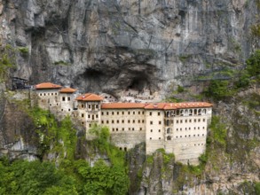Monastery built into the rock with red roofs, surrounded by steep rock faces, aerial view, Sumela