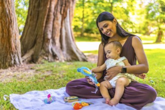 Latin mother and daughter enjoying a sunny day at the park, playing with colorful toys and creating