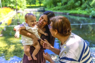 Latin family, including a grandmother, mother, and baby daughter, are enjoying quality time