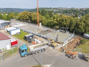 Aerial view of a construction site with large vehicles and active construction work, car park