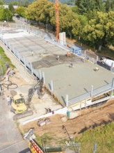 Workers and machines concreting on a construction site under a large crane, car park construction,