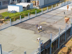 Construction workers working on a concrete surface on a building site in a green environment, car