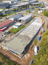 Industrial area with construction site, crane and buildings, bird's eye view, car park