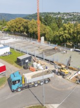 Truck and crane on an active construction site in a green, urban environment, car park