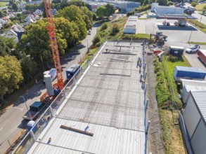 Crane over a construction site with workers and surrounding streetscape and landscape, car park