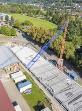 Aerial view of a construction site with crane and partially constructed building surrounded by