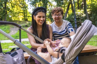 Grandmother, mother, and baby girl enjoying quality time together in a park, highlighting the joys