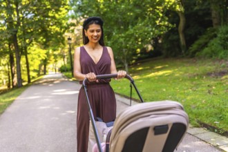 Latin mother enjoying a walk in the park, pushing a stroller with her baby inside, on a sunny day