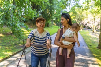 Grandmother, mother, and baby girl enjoying a sunny day at the park, pushing a stroller and