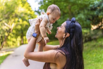 Happy latin mother lifting her baby high in the air, enjoying playful moments and laughter in a
