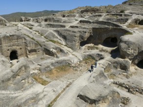 Archaeological site with sandstone cave structures under a clear sky, aerial view, Uplistsikhe cave