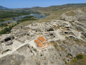Lonely ancient ruins of Uplistsikhe with orange-coloured roof in the middle of a vast landscape,