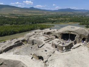 Ancient ruins with tourist visitors, surrounded by river landscapes and mountains, aerial view,