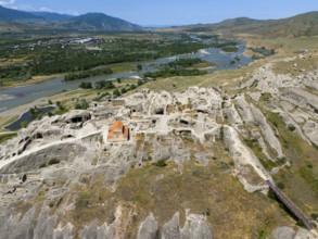 Panoramic view of a rocky landscape with embedded church and river view, aerial view, cave town