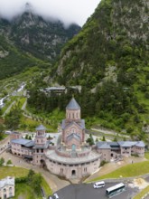 Majestic red brick church in a picturesque mountain landscape under cloudy atmosphere, aerial view,