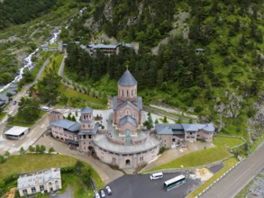 Red brick church in a picturesque mountain landscape, surrounded by forests and clouds in the sky,