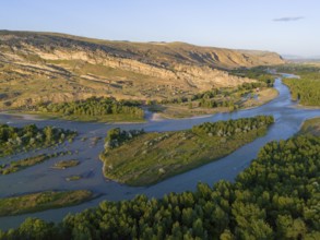 Extensive river landscape with green islands and rocky cliffs, framed by forest areas under a clear