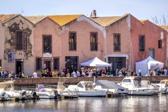Sardinia, boats in the river Temo and houses on the promenade, guests at the restaurants with