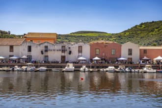 Sardinia, boats in the river Temo and residential buildings on the promenade, guests at the