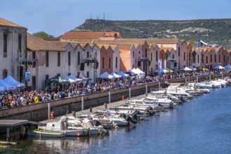 Sardinia, boats in the river Temo and houses on the promenade, guests at the restaurants with