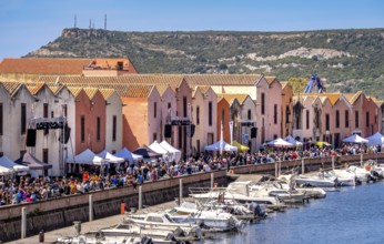 Sardinia, boats in the river Temo and houses on the promenade, guests at the restaurants with
