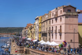 Sardinia, boats in the river Temo and houses on the promenade, guests at the restaurants with