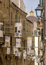 Sardinia, lanterns made of fabric remnants patchwork on power lines between the houses above the