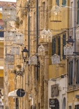 Sardinia, birdcage with light bulbs on power lines between houses above the alleyway, old town,
