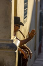 An old Cuban smokes a cigar and sits on a staircase in the warm light of the sunset, Trinidad,