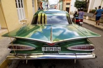 Vintage car, historic road cruiser, green Impala, streetlife in the city centre of Santa Clara at