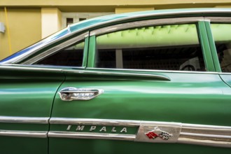 Vintage car, historic road cruiser, green Impala, streetlife in the city centre of Santa Clara at