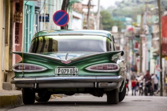 Vintage car, historic road cruiser, green Impala, streetlife in the city centre of Santa Clara at