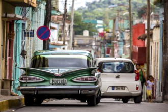 Vintage car, historic road cruiser, green Impala, streetlife in the city centre of Santa Clara at