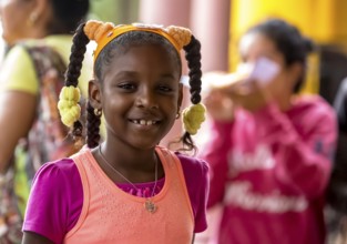 Young girl with pinned-up pigtails at a Cuban pizza stand with her family, Viñales, Cuba, Pinar del