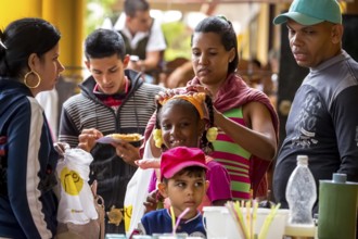 Young girl with pinned-up pigtails at a Cuban pizza stand with her family, Viñales, Cuba, Pinar del
