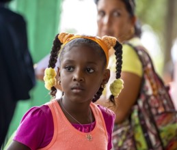 Young girl with pinned-up pigtails at a Cuban pizza stand with her family, Viñales, Cuba, Pinar del