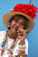 Old Cuban woman smokes a Cuban cigar on the street and posts with her cat for the tourists, La