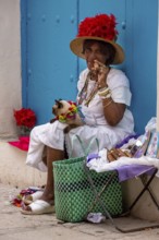 Old Cuban woman smokes a Cuban cigar on the street and posts with her cat for the tourists, La
