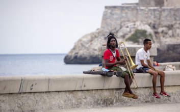 Young Cubans on the walls of the Malecon trombonist, musicians outdoors with dreadlocks, La Habana,