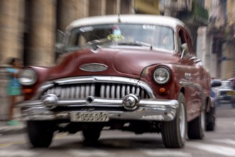 Red vintage car in street scene, Old American road cruiser on the streets of Havana, taxi, La