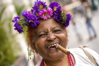 Old Cuban woman with flowers and cigar posing for a tip for tourists, La Habana, Havana, Cuba,