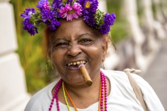 Old Cuban woman with flowers and cigar posing for a tip for tourists, La Habana, Havana, Cuba,