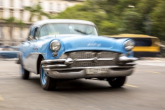 Speed, blurred, moving old car, blue oldtimer in street scene, old american street cruiser on the