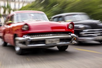 Speed, blurred, moving old car, red oldtimer in street scene, old american street cruiser on the