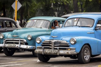Turquoise and blue vintage car in street scene, Old American road cruiser on the streets of Havana,