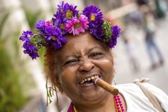 Old Cuban woman with flowers and cigar posing for a tip for tourists, La Habana, Havana, Cuba,