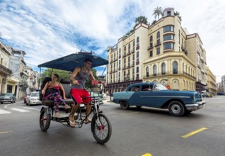 Oldtimer in street scene, bicycle rickshaw, human taxi on the street crossing at the Hotel
