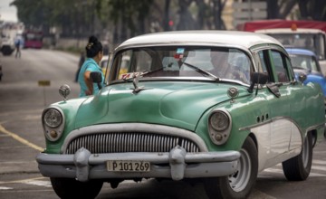 Green vintage car in street scene, Old American street cruiser on the streets of Havana, Taxi, La
