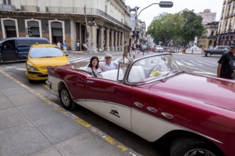 Tourists in a red convertible, red vintage convertible in the street scene, old American street